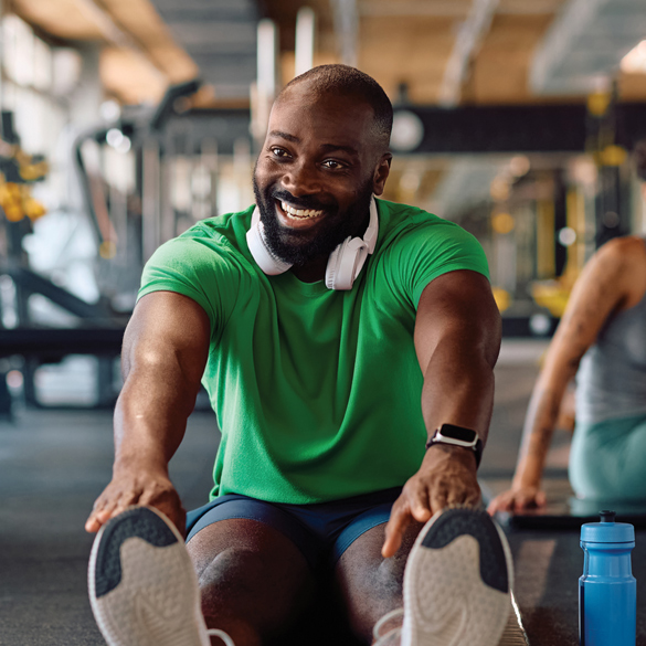 Man stretching his legs while seated, facing the camera, and smiling.